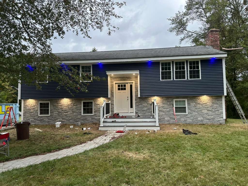 Split-level home with new dark blue siding and stone veneer